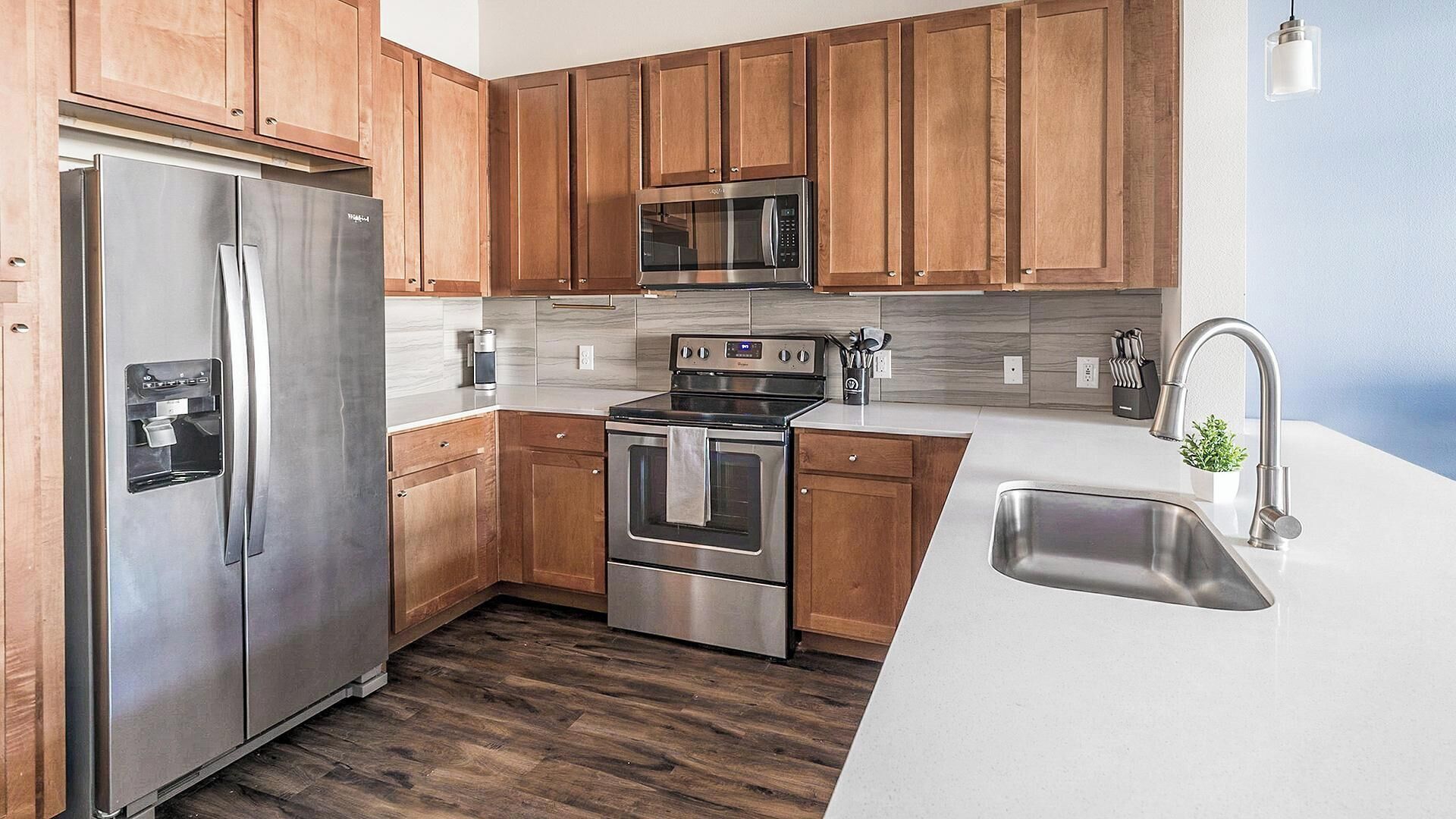 A modern kitchen with wooden cabinets, stainless steel appliances, a built-in microwave, and a sink.