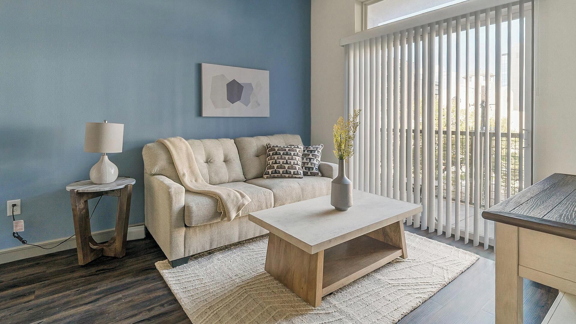A living room with a sofa, a coffee table, a lamp, and a painting on the wall.