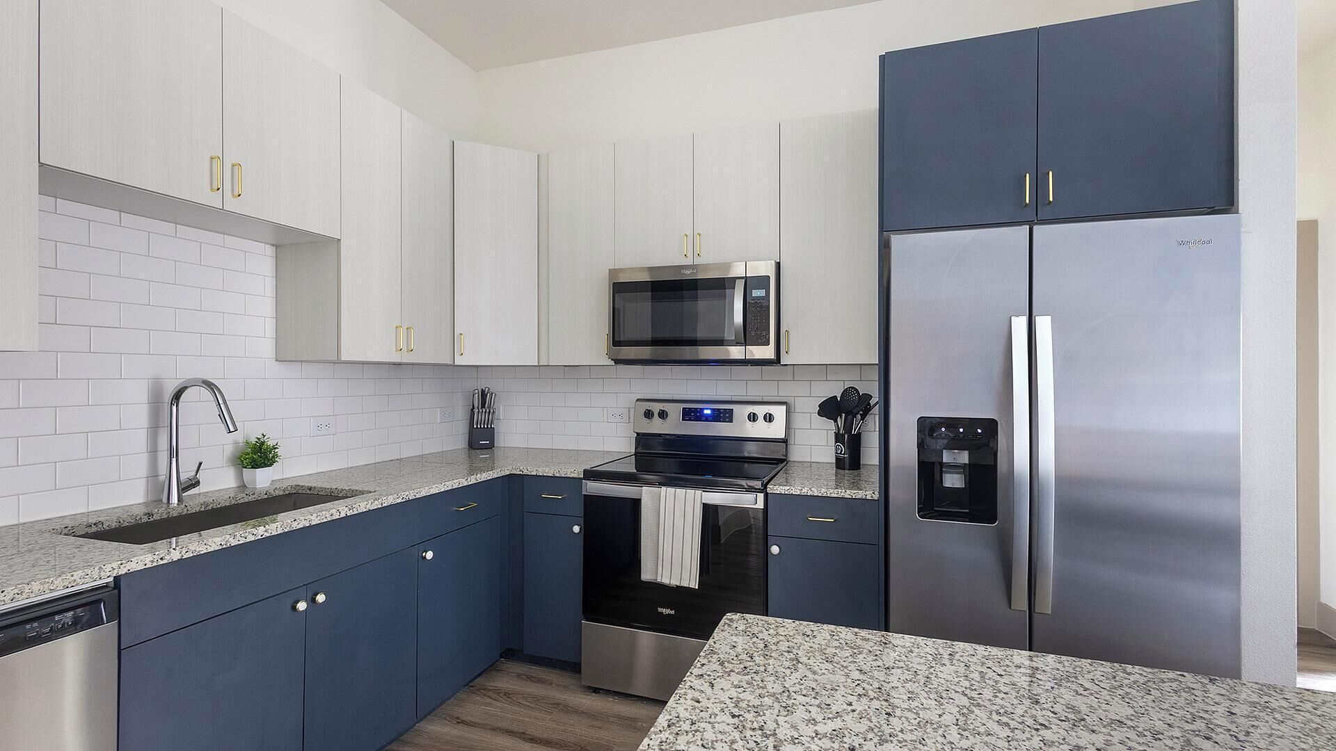 A modern kitchen with white cabinets, stainless steel appliances, and a granite countertop.