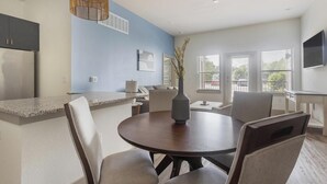 Una cocina moderna con horno empotrado, un comedor con mesa redonda y un amplio ventanal con persianas.