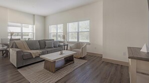 A living room with a sofa, coffee table, and a dining area with a table and chairs. - Landing | Amazing 2BD, Courtyard, Gym (Houston)