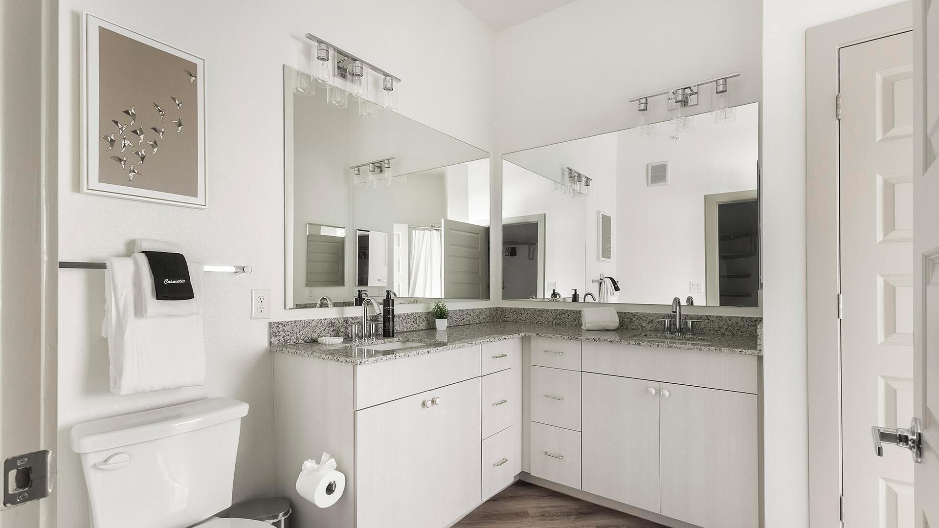A modern bathroom with a toilet, sink, and large mirrors.