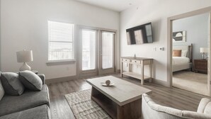 Een moderne slaapkamer met een bed, bureau, televisie en een slaapbank.