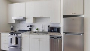 Een moderne keuken met roestvrijstalen apparatuur, witte kastjes en een granieten aanrecht.