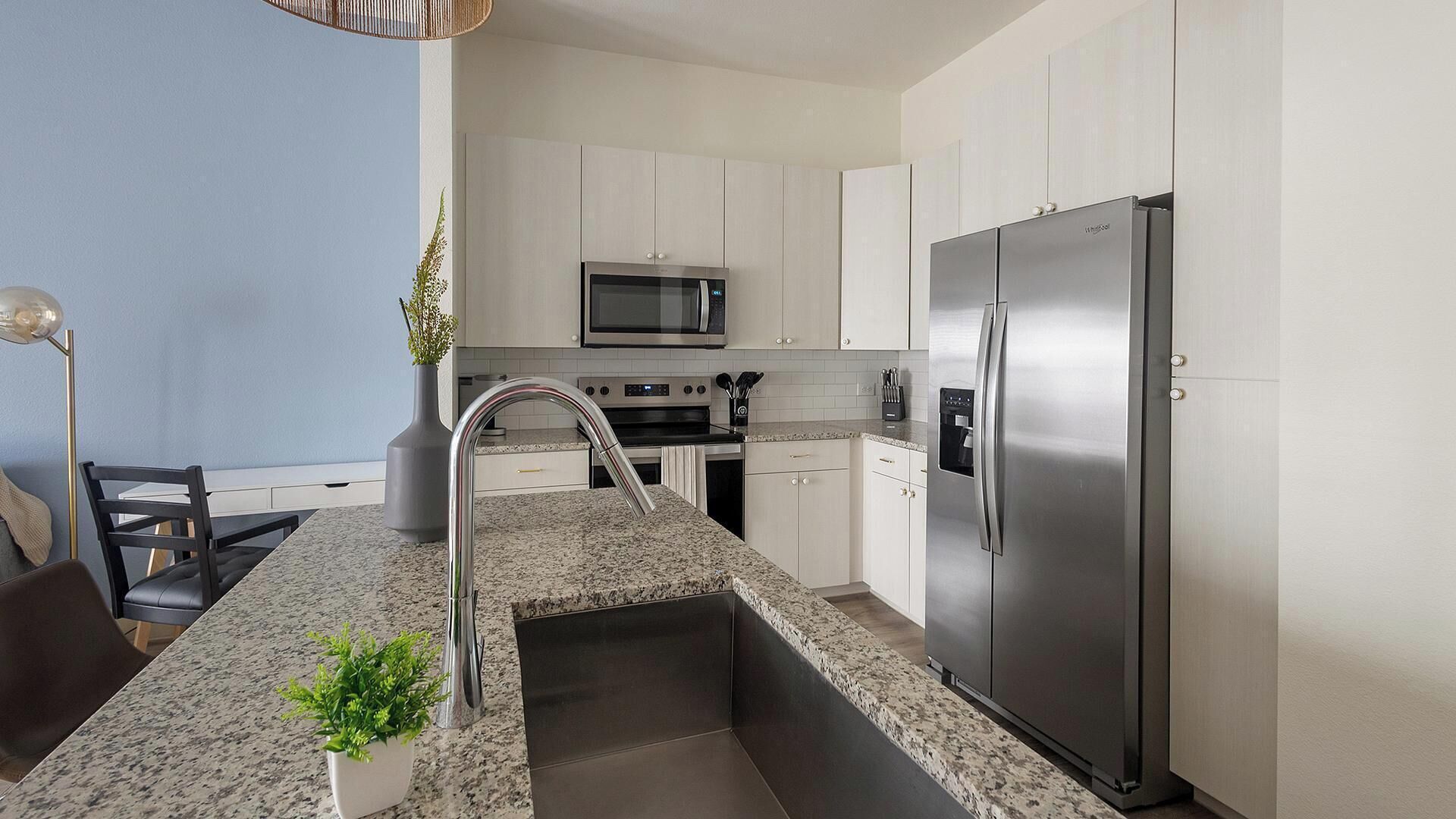 A modern kitchen with a stainless steel refrigerator, a microwave, and a sink with a modern faucet.