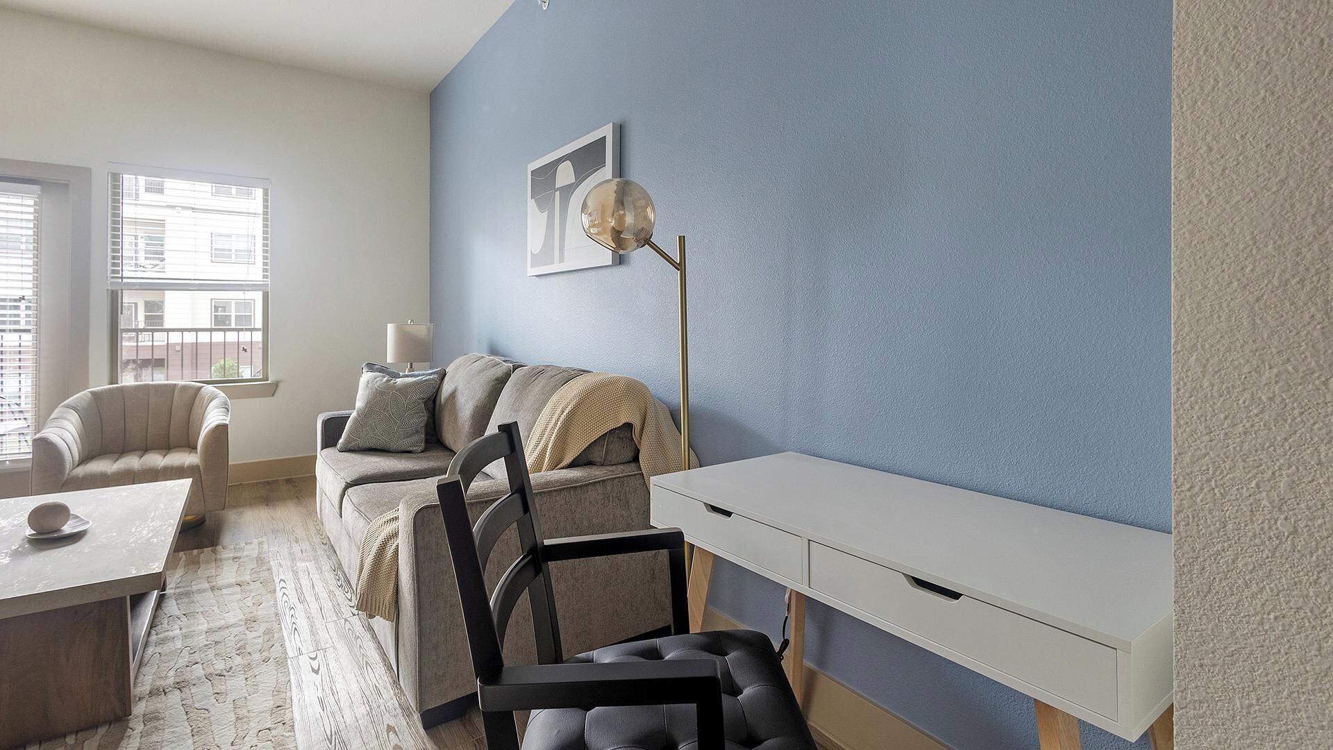 Un salon moderne comprenant un canapé, des fauteuils, une table basse et un bureau.