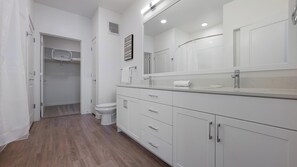 A modern bathroom with a large mirror, white cabinets, and a shower area. - Landing | Incredible 1BD, Gym, Clubhouse (Austin)