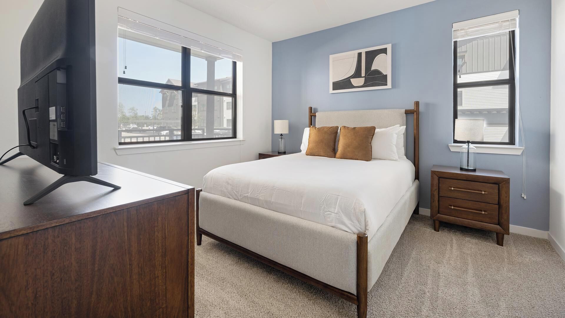 Un dormitorio con cama, mesitas de noche, un escritorio y televisión.