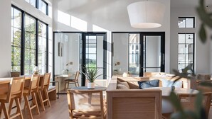 A spacious living area with large windows, a dining table, and a seating arrangement. - Landing | Chic 2BD, Clubhouse, Gym (Austin)