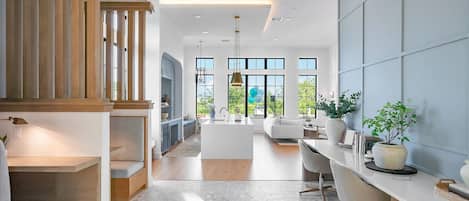 A modern kitchen with a central island, a dining area with a white table and chairs, and a living room with a sofa and a coffee table.