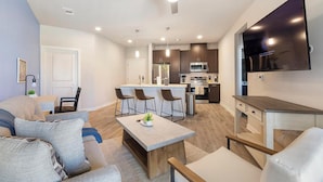 Un apartamento moderno con sala de estar, comedor, cocina y un televisor instalado en la pared.