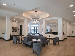 A spacious lobby with a modern chandelier, seating areas, and a visible bar area. - Landing | Beautiful 1BD, Pool, Clubhouse (Denton)