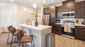 Una cocina moderna con una isla central, electrodomésticos de acero inoxidable y armarios de madera oscura.