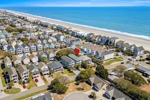 Un quartier résidentiel situé sur la côte, avec des maisons, une plage et une jetée en arrière-plan.