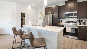 Una cocina moderna con una isla central, electrodomésticos de acero inoxidable y armarios de madera oscura.