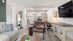 Un apartament modern amb saló, menjador, cuina i televisió penjada a la paret.
