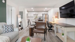 A modern apartment with a living room, dining area, kitchen, and a TV mounted on the wall. - Landing | Modern 2BD, Gym, Clubhouse (Kissimmee)