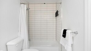 A bathroom with a shower, toilet, and a towel rack. - Landing | Stylish Studio, Gym, Pool (Kissimmee)