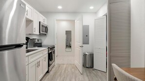 A compact kitchen with stainless steel appliances, a microwave, and a trash bin. - Landing | Stylish Studio, Gym, Pool (Kissimmee)