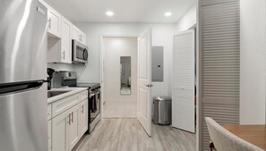 A compact kitchen with stainless steel appliances, a microwave, and a trash bin. - Landing | Beautiful Studio, Pool, Clubhouse (Kissimmee)