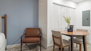 Une pièce avec un fauteuil en cuir marron, une table ronde en bois et un mur blanc avec une fenêtre.