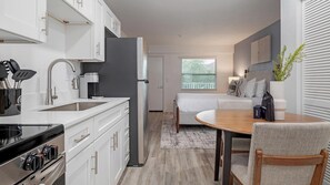 A modern kitchen with white cabinets, a stainless steel range, and a coffee machine. - Landing | Chic Studio, Clubhouse, Gym (Kissimmee)