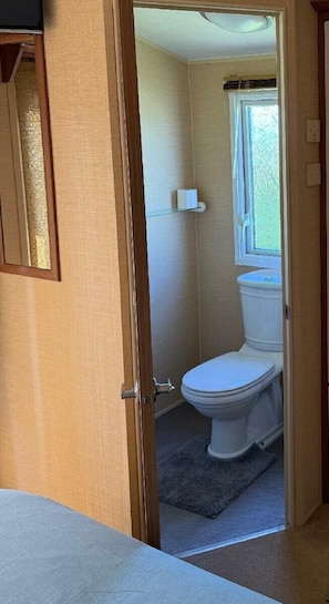 A bathroom with a toilet, a window, and a shower. - Happy Days Caravan Park - Holiday Accommodation 21912 (Abergele)