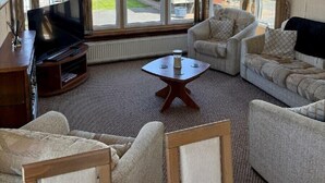 A living room with a television, two sofas, a coffee table, and large windows. - Happy Days Caravan Park - Holiday Accommodation 21912 (Abergele)