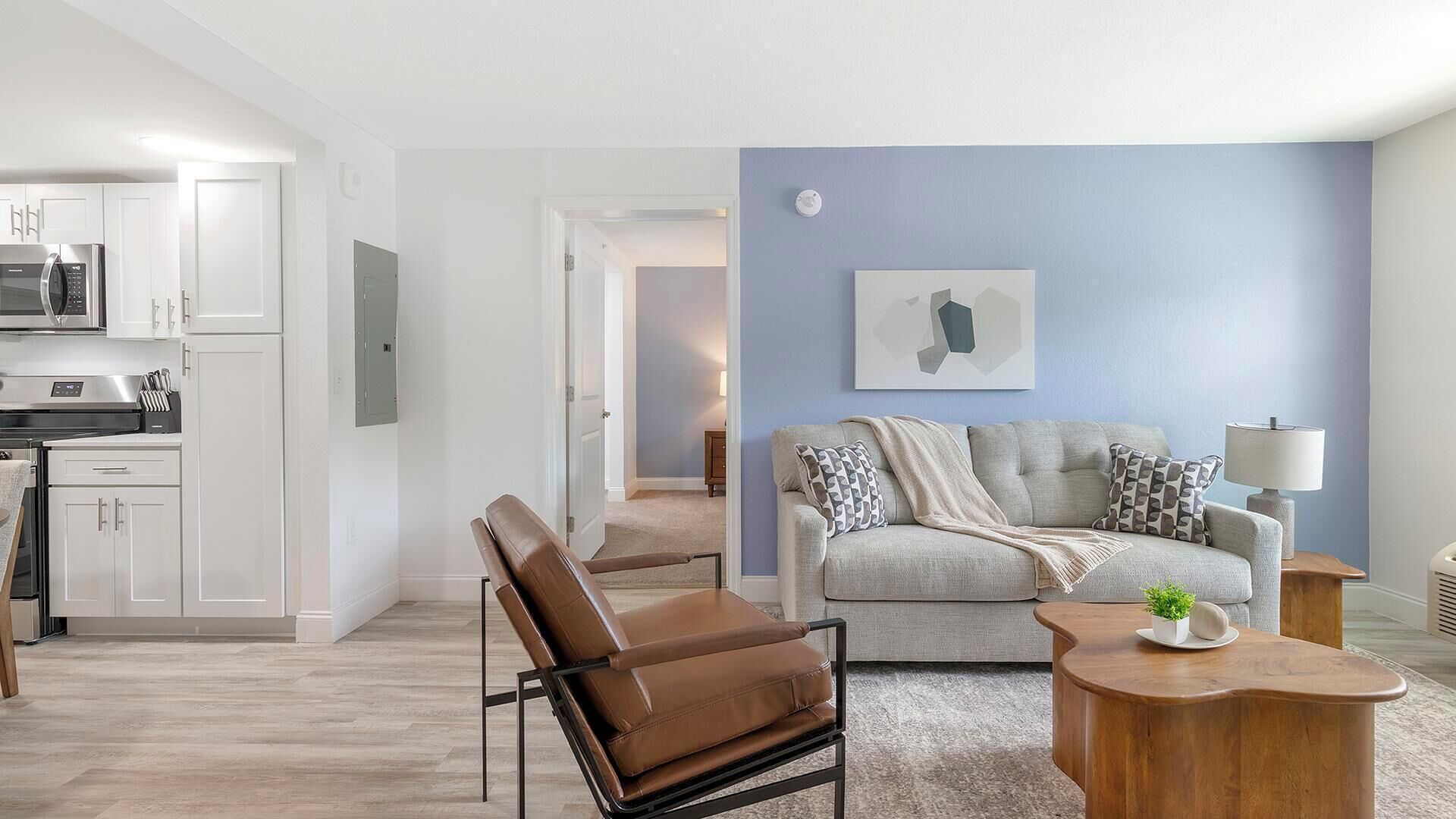 A modern living room with a sofa, a leather chair, and a wooden side table.