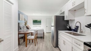 Una cocina compacta con refrigerador, pileta y alacenas. Hay un comedor con mesa y sillas.