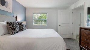 A bedroom with a bed, a window, a door, and a dresser. - Landing | Beautiful 1BD, Pool, Clubhouse (Kissimmee)