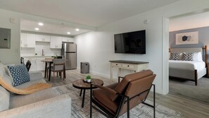 A modern apartment with a kitchenette, a dining area, a living room with a TV, and a bedroom. - Landing | Beautiful 1BD, Pool, Clubhouse (Kissimmee)