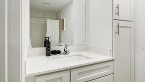 A bathroom with a white sink, a mirror, a shower curtain, and a toilet. - Landing | Stunning Studio, Pool, Clubhouse (Kissimmee)