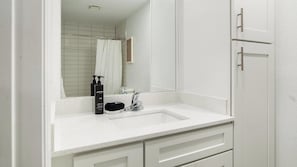 A bathroom with a white sink, a mirror, a shower curtain, and a toilet. - Landing | Beautiful Studio, Pool, Gym (Kissimmee)