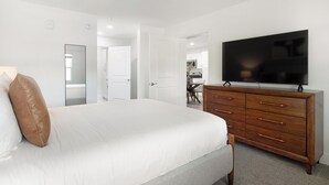 Ein Schlafzimmer mit einem großen Bett, einer Holzkommode und einem Flachbildfernseher.