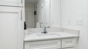A bathroom with a white sink, a mirror, and a shower area. - Landing | Chic Studio, Pool, Clubhouse (Kissimmee)