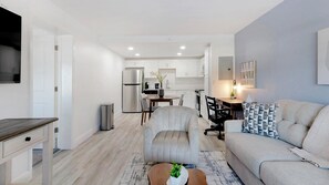 A modern living room with a sofa, a coffee table, and a dining area with chairs and a table. - Landing | Stylish 1BD, Clubhouse, Gym (Kissimmee)
