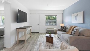 Un salon avec un téléviseur, un canapé, une table basse et une fenêtre donnant sur un beau paysage.