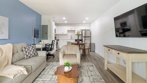A modern living room with a sofa, coffee table, and TV. - Landing | Incredible 1BD, Pool, Gym (Kissimmee)