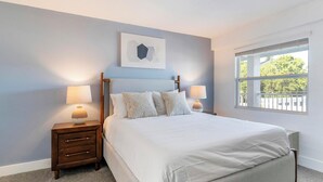 A bedroom with a bed, two bedside tables, a window, and a wall-mounted artwork. - Landing | Stunning 1BD, Clubhouse, Pool (Kissimmee)