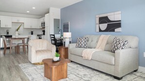 Un salon moderne comprenant un canapé, un fauteuil, une table basse et un coin repas avec une table et des chaises.