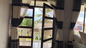 A room with a sliding glass door leading to a balcony, a white sofa, and a small table. - Kigotho Hotel & Apartments (Mombasa)