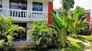 A two-story building with a balcony, surrounded by lush greenery and a well-maintained garden. - Kigotho Hotel & Apartments (Mombasa)