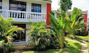 A two-story building with a balcony, surrounded by lush greenery and a well-maintained garden. - Kigotho Hotel & Apartments (Mombasa)