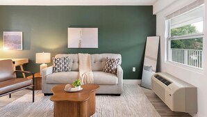 Ein Wohnzimmer mit einer Couch, einem Couchtisch, einer Lampe, einem Heizkörper und einem Fenster.