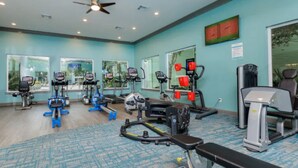 Une salle de sport équipée de machines de cardio, de postes d’entraînement avec poids et d’un banc.