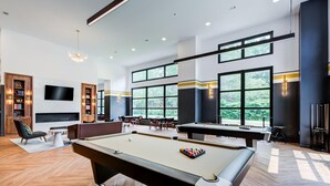 A modern indoor pool area with a pool table, seating, and large windows. - Landing | Stunning 1BD, Game Room, Yoga Studio (New Haven)