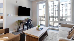 Ein modernes Wohnzimmer mit Flachbildfernseher, Schreibtisch und Sofa.