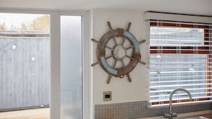 Eine Küche mit Schiffslaugem und einem Fenster mit Jalousien, sowie ein Spülbecken.