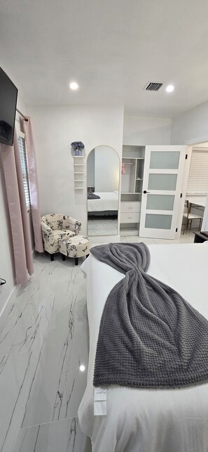 Ein Schlafzimmer mit Bett, Stuhl, Kleiderschrank und Spiegel.